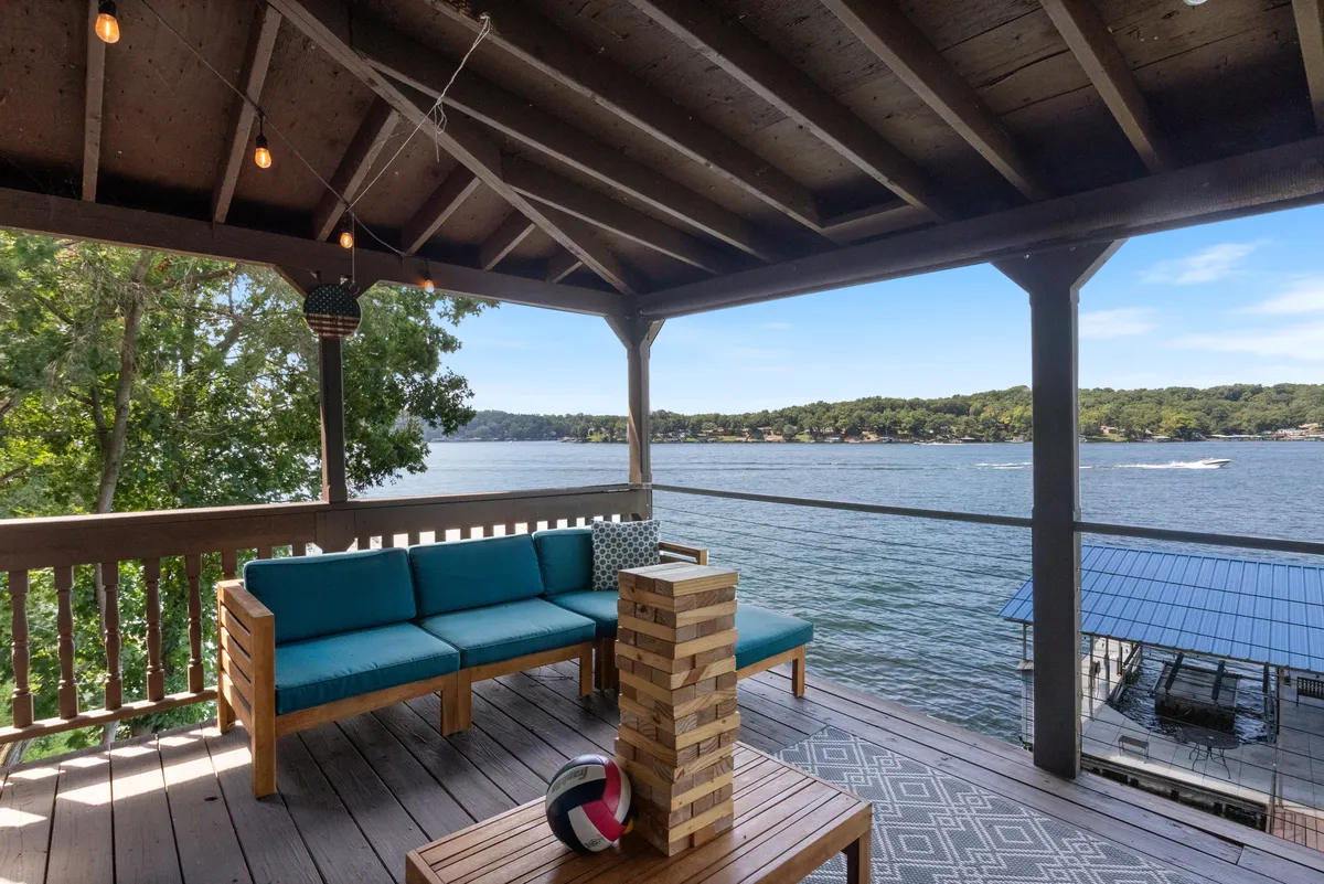 An inviting exterior seating area by the lake featuring a Jenga game on the table and a decorative volleyball, set against the backdrop of serene water views. The area encourages play and social gatherings.