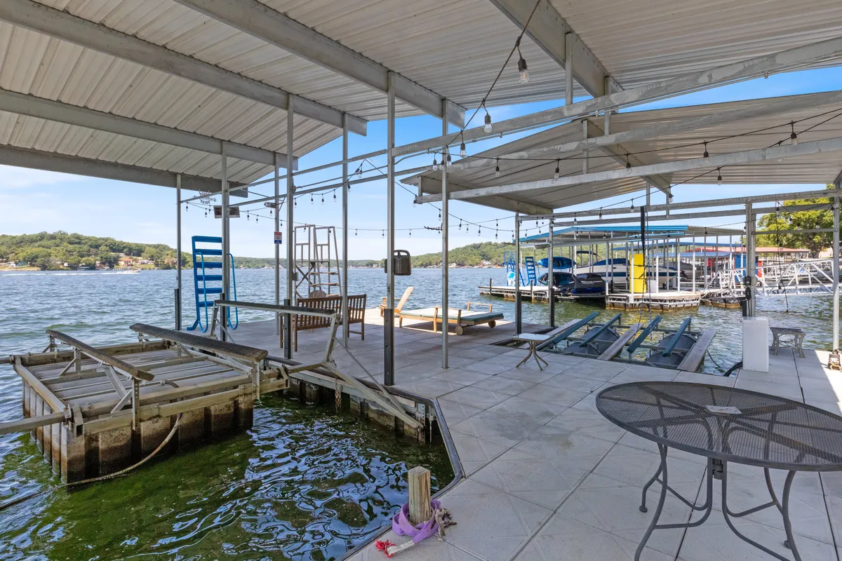 The image captures a spacious dock area with visible boat slips, a comfortable seating arrangement, and panoramic lake views. The scene invites a variety of lakefront activities—boating, swimming, and unwinding by the water.