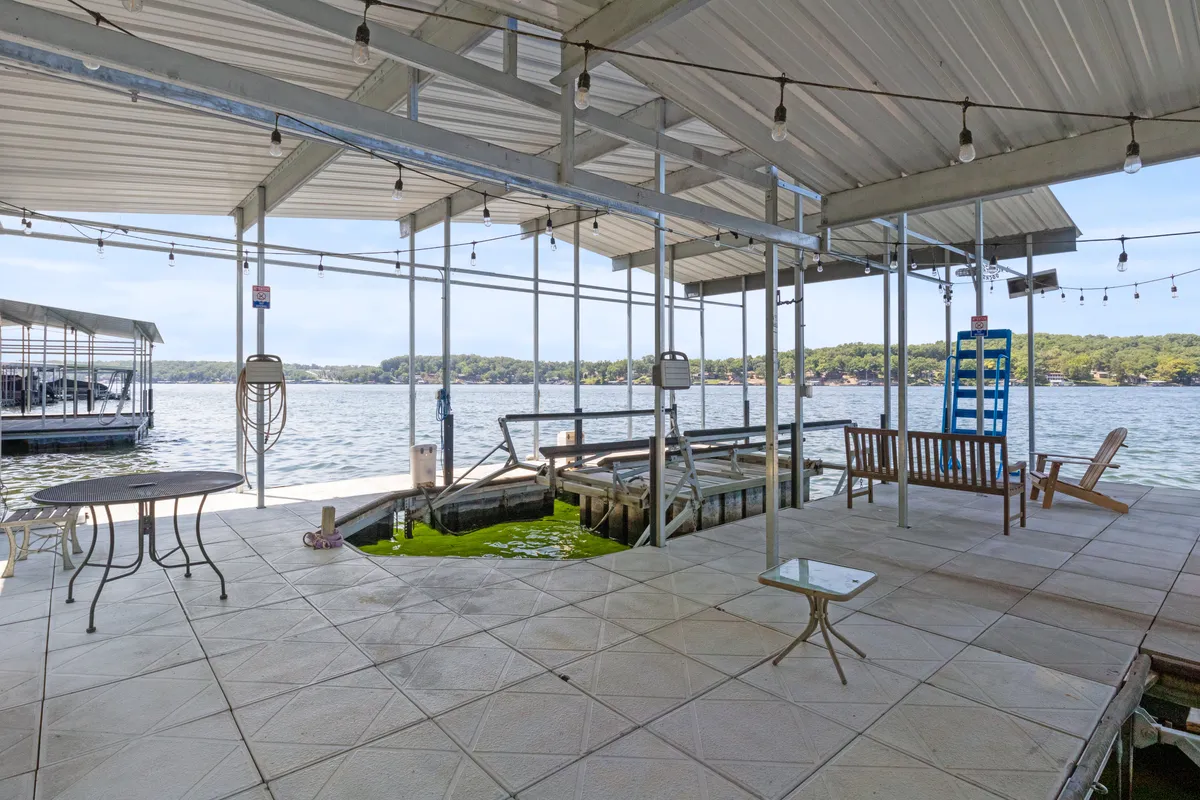 A well-appointed dock extends over the sparkling water with a cozy seating area and tables. Hanging lights add ambiance for evening gatherings, while the dock itself invites activities like fishing, diving, and enjoying sunsets.